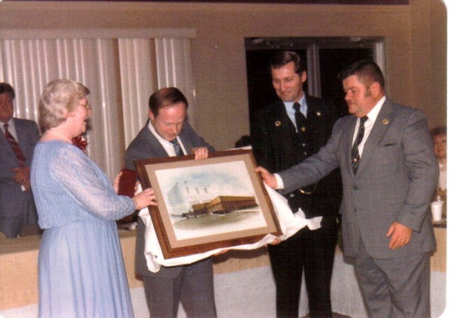 Department Members Billy Simpson, Andy McWilliams and Joe Guyther receive a painting of the &quot;new&quot;and the &quot;old&quot; Fire Stations from Teeny Simpson. This Painting hangs in the Department Social Hall Today